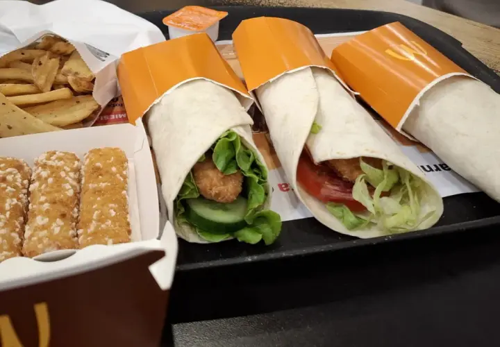 Trzy mcwrap klasyczny z kurczakiem, warzywami i sosem. Obok frytki i paluszki serowe. Idealny zestaw na szybki posiłek, z uwzględnieniem kcal.