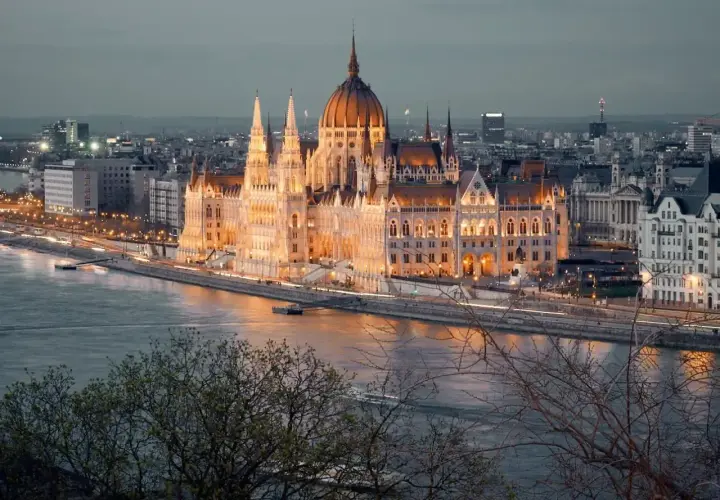 Wspaniały Parlament w Budapeszcie o zmierzchu, oświetlony i odbijający się w Dunaju. Obowiązkowy punkt, co zobaczyć w Budapeszcie.
