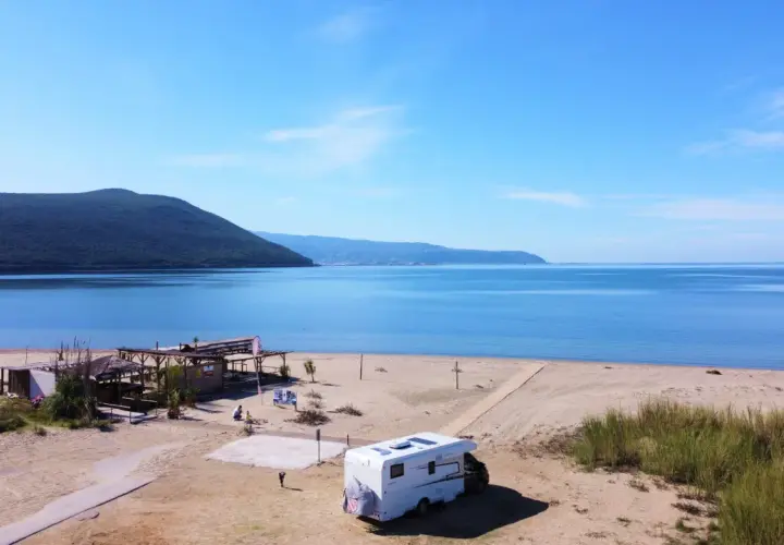 Kamper na piaszczystej plaży w Grecji kontynentalnej, z widokiem na spokojne morze i zalesione wzgórza. Idealne miejsce na wakacje.