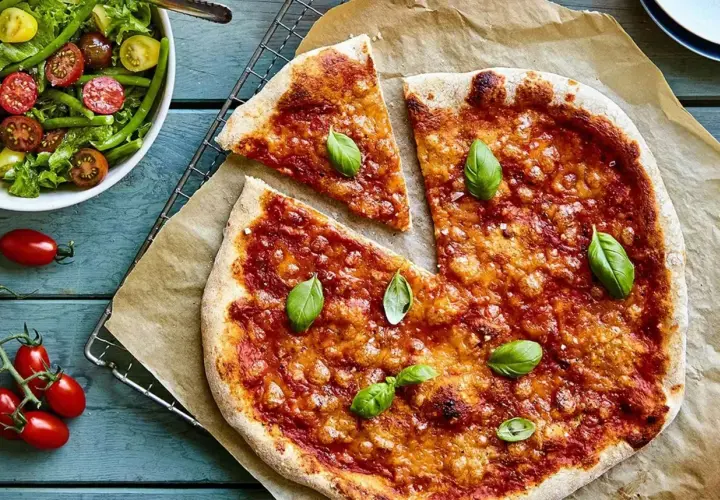En nybakad liba pizza med tomatsås och basilika, serverad med en fräsch sallad.