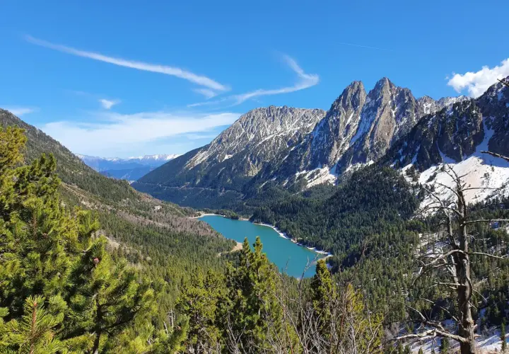 Lago turquesa rodeado de bosques y montañas nevadas, un paisaje espectacular cerca de Esterri d'Àneu.