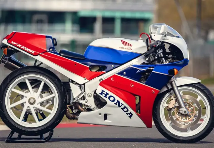 La icónica Honda RC30 VFR750R, con su distintivo tricolor rojo, blanco y azul, lista para la pista.