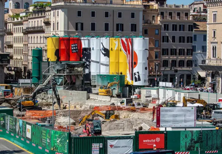Cantiere per i lavori metro Roma con grandi teli colorati e macchinari edili.