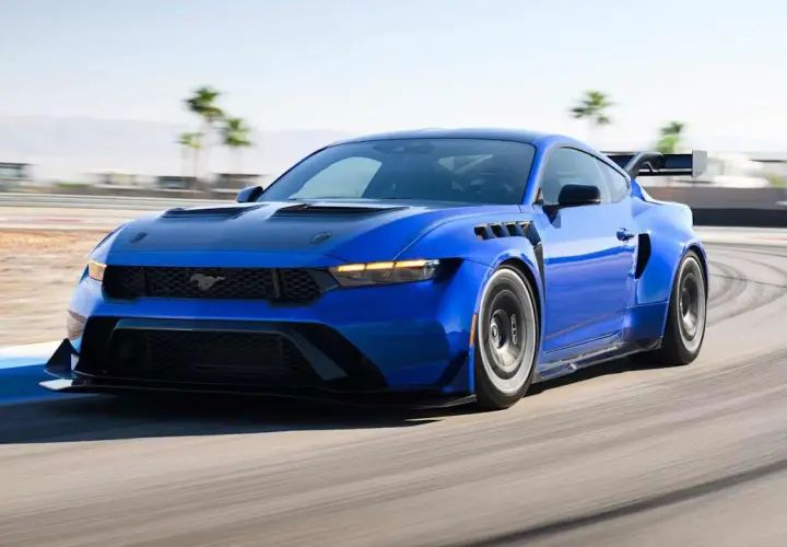 Blauer Mustang GTD rast auf Rennstrecke, mit breiten Kotflügeln und großem Heckspoiler.