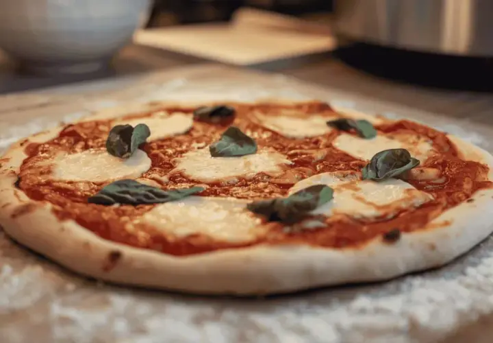 Une délicieuse pizza Margherita, avec sa pâte à pizza maison, prête à être dégustée. Un vrai délice pour les amateurs de pain et de bonnes choses.