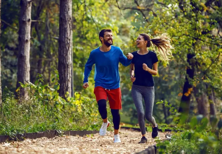 Szczęśliwa para cieszy się wspólnym trail run w jesiennym lesie.