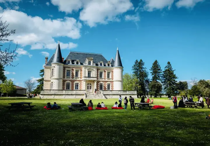 Visite d'un magnifique château dans le Médoc, avec des gens profitant du soleil sur la pelouse.