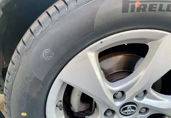 Un neumático Pirelli con un punto amarillo, marca de fábrica, y un pequeño círculo con una cara sonriente en el flanco.