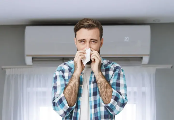 Hombre con pañuelo en la nariz, con aire acondicionado de fondo. Podría ser que se puede tener alergia al aire acondicionado.