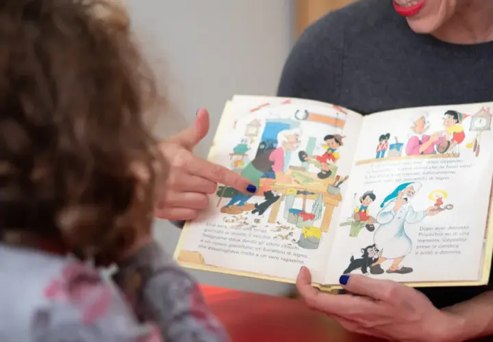 Donna legge un libro illustrato a un bambino, un momento di apprendimento che supporta il rinnovo certificazione DSA.