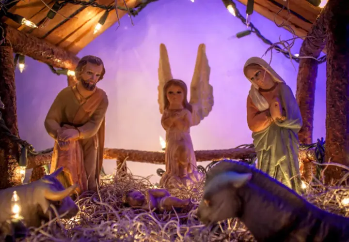 Portal de Belén manualidades: figuras de San José, la Virgen María, un ángel, el Niño Jesús, un buey y una mula, iluminados con luces navideñas.