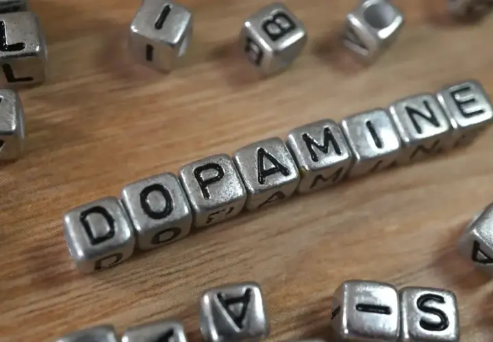 Cubos plateados forman la palabra "DOPAMINE". Descubre cómo aumentar tu dopamina para sentirte mejor.