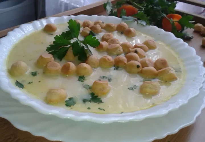 Aksamitna zupa z groszkiem ptysiowym, udekorowana natką pietruszki, czeka na spróbowanie.