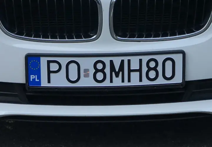 Biały samochód z polską tablicą rejestracyjną PO 8MH80.