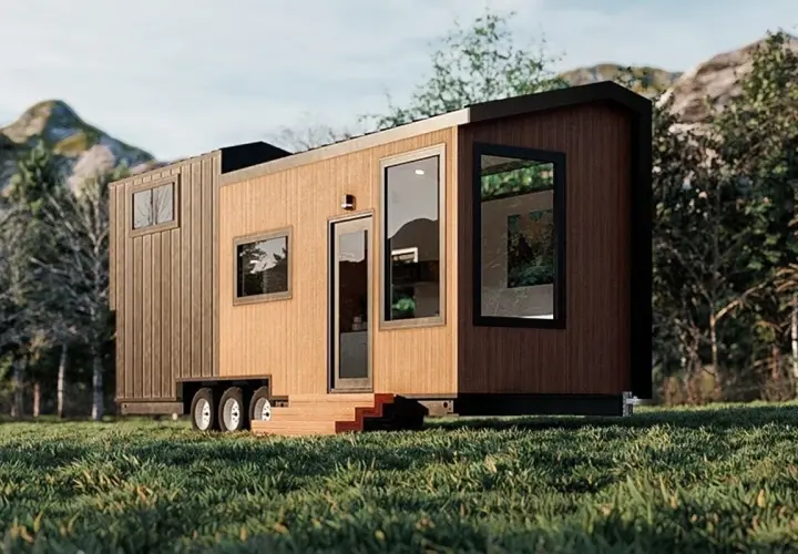 Tiny house sur roues dans un paysage verdoyant. La question "un particulier peut il acheter une maison en zone agricole" se pose face à ce type d'habitat.