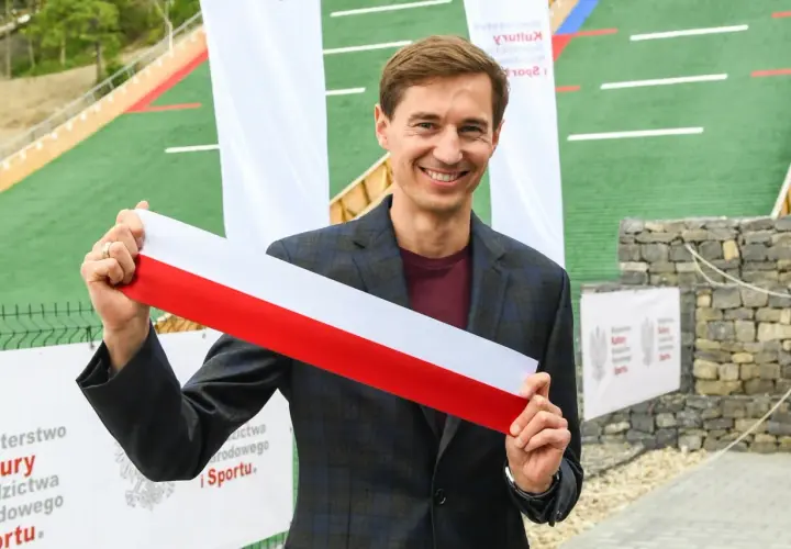 Uśmiechnięty mężczyzna trzyma biało-czerwoną wstęgę. Czy to symbol otwarcia obiektu, który ma ile lat stoch?