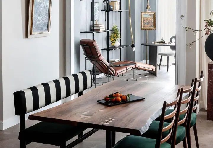 A large, live-edge wooden table with inlaid details, showcasing its impressive table dimension, is set with a tray of tangerines.