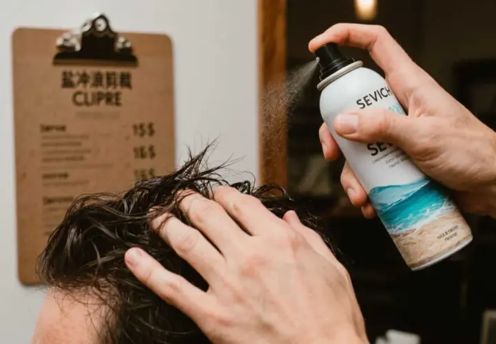 Un hombre aplica spray sal marina pelo para un look playero.