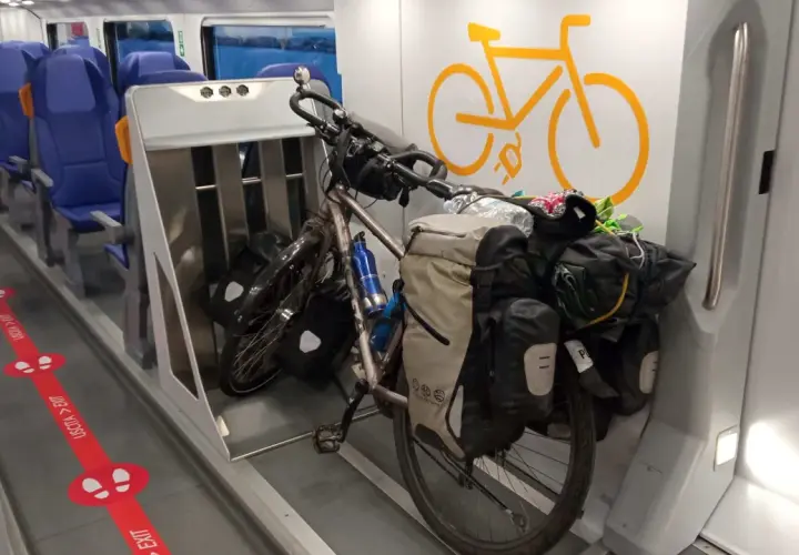 Rowerzysta w podróży: rower z sakwami gotowy do transportu w specjalnym wagonie rowerowym w pociągu.