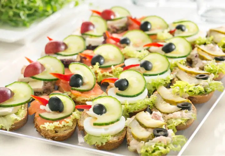 Kolorowe kanapki na talerzu, idealne na pan kanapka catering. Różne dodatki: łosoś, jajko, ogórek, oliwki, winogrona.