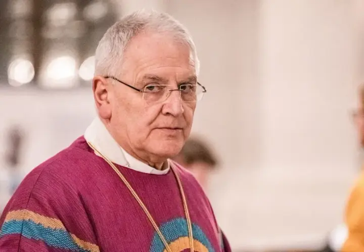 Bischof Heinrich Timmervers trägt ein violettes Messgewand mit bunten Streifen. Er blickt ernst in die Kamera.