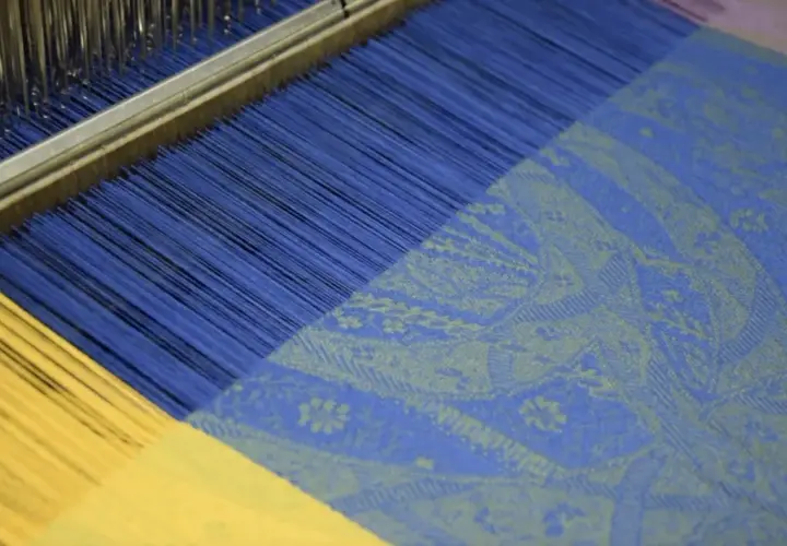 Le métier à tisser jacquard crée un motif complexe sur un tissu bleu et jaune.