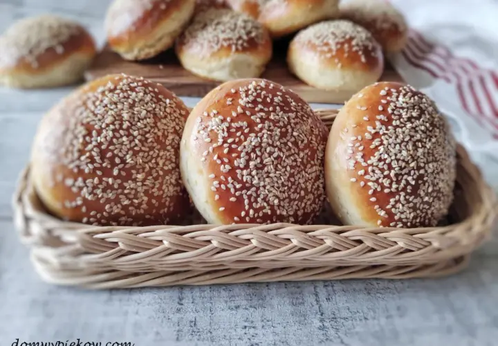 Świeżo upieczone bułki do burgerów, posypane sezamem, w wiklinowym koszyku. Idealne na domowe burgery.