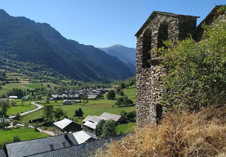 Vista del pueblo de Vall Ferrera con su campanario de piedra y montañas verdes al fondo.