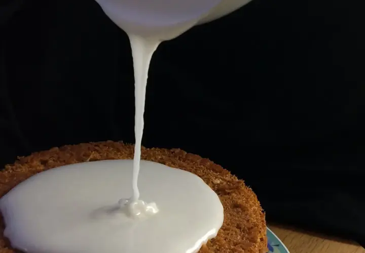Zuckerguss Rezept: Ein Kuchen wird mit flüssigem Zuckerguss überzogen.