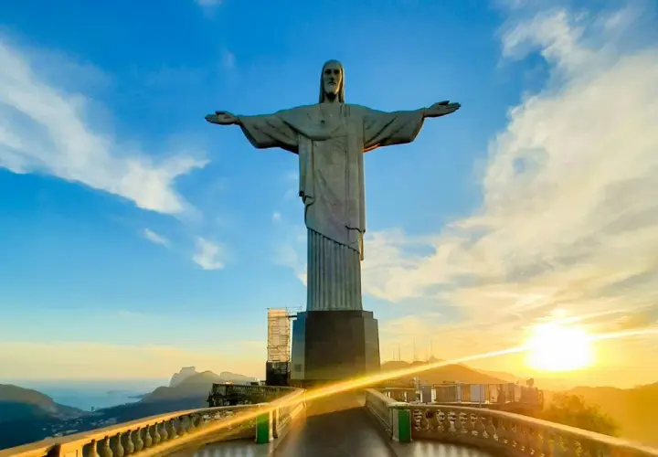 Christusstatue in Brasilien mit weit ausgebreiteten Armen, die den Sonnenuntergang über Rio de Janeiro überblickt.