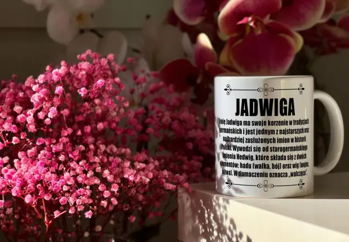 Kubek z napisem "Jadwiga" i opisem imienia, otoczony delikatnymi, różowymi kwiatami. Idealny prezent na imieniny Jadwigi.