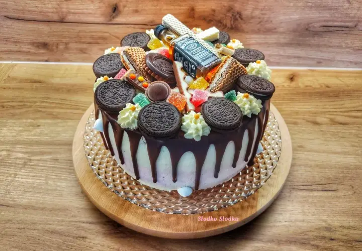 Wyjątkowy tort z polewą czekoladową, ozdobiony ciasteczkami Oreo, waflowymi rurkami, żelkami i mini buteleczką Jack Daniel's.