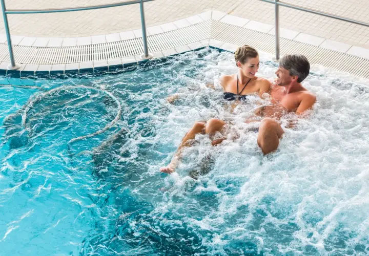 Para relaksująca się w jacuzzi, para uśmiecha się do siebie.