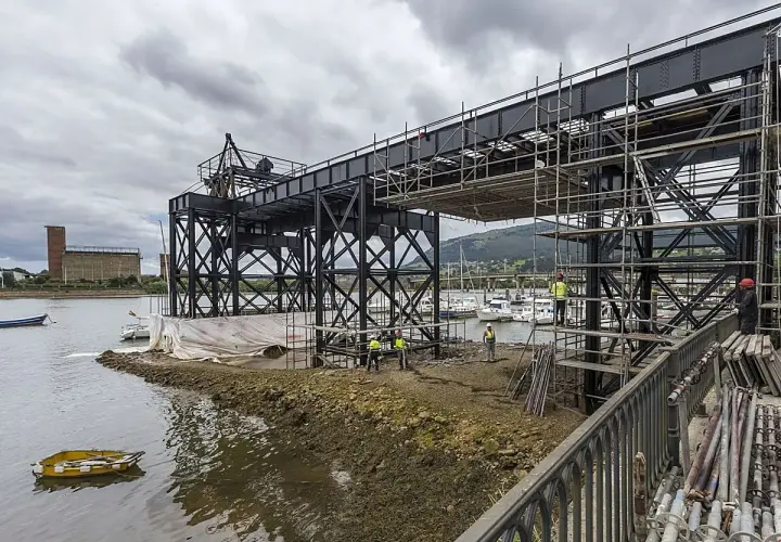 Obras en el puente de Santander, con andamios y trabajadores junto a la ría. Yates amarrados al fondo.