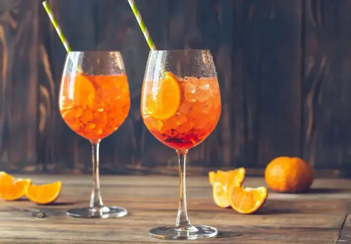 Dwa orzeźwiające Aperol Spritze z plastrem pomarańczy i słomkami. Aperol ma 11% alkoholu, idealny na letnie popołudnie.