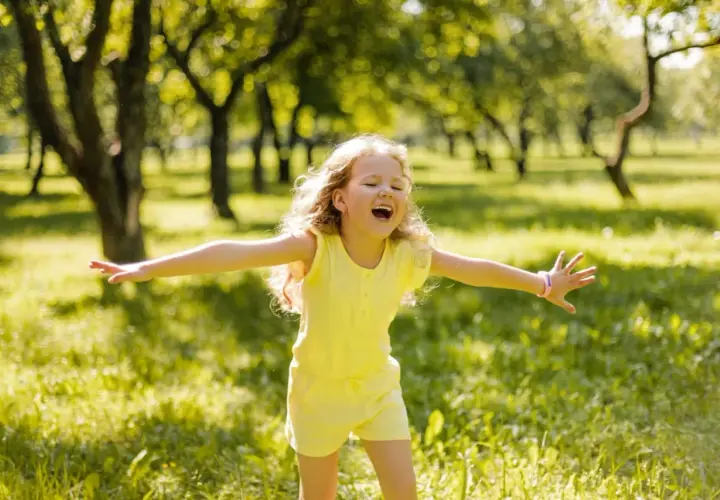 Niña feliz en un parque, disfrutando del sol. Su alegría refleja la autoestima en niños de 9 a 12 años.