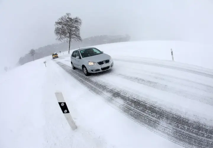 Coches circulando por carreteras con nieve en un día de invierno con poca visibilidad.