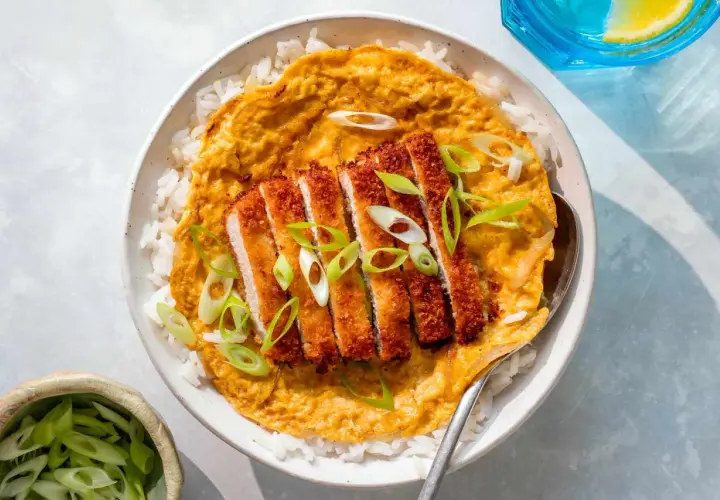 A delicious katsu don with crispy pork cutlet over rice, topped with a savory egg mixture and garnished with fresh scallions.