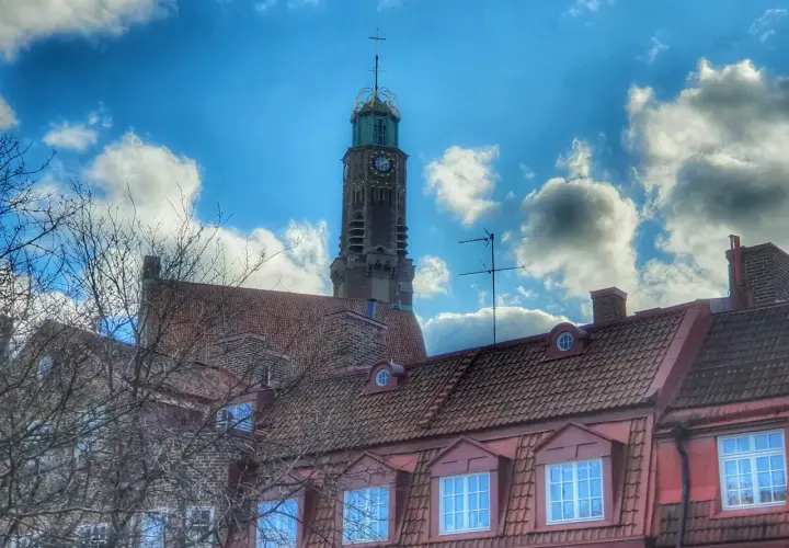 Engelbrekts kyrka reser sig mot en dramatisk himmel med moln. Kyrktornet har en klocka och en grön kupol.