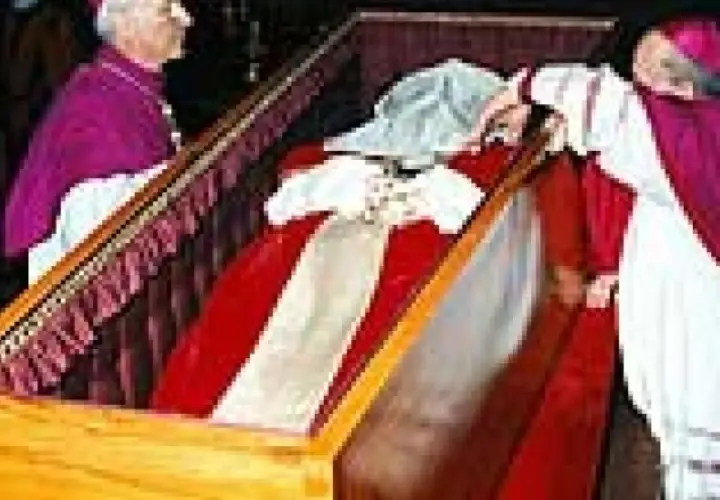 Würdenträger bei der Umbettung von Johannes Paul II. im Sarg, der mit rotem Stoff und weißen Bändern geschmückt ist.