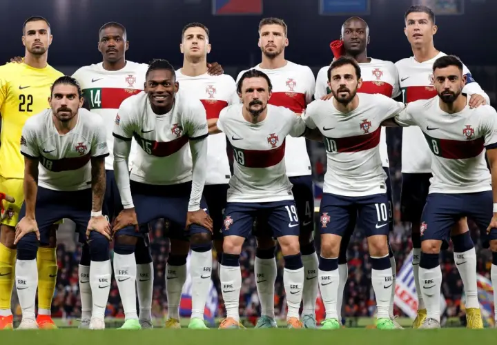 Drużyna piłkarzy Portugalii w białych strojach z czerwonym pasem, gotowa do meczu.