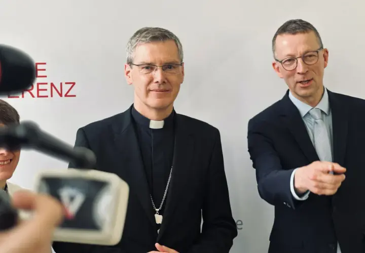 Der Vorsitzende der Deutschen Bischofskonferenz, Georg Bätzing, im Gespräch mit einem Mann im Anzug.