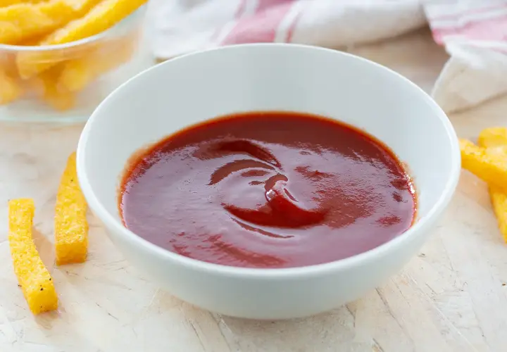Ciotola di ketchup fatto in casa, con bastoncini di polenta fritta intorno.