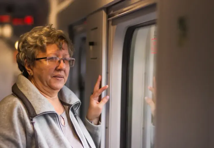 Starsza pani w okularach, podróżująca pociągiem PKP Intercity, cieszy się z 70 lat darmowych przejazdów.