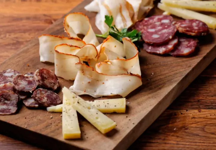 Un invitante tagliere di antipasti con salumi affettati, formaggio e lardo su un tagliere di legno rustico.
