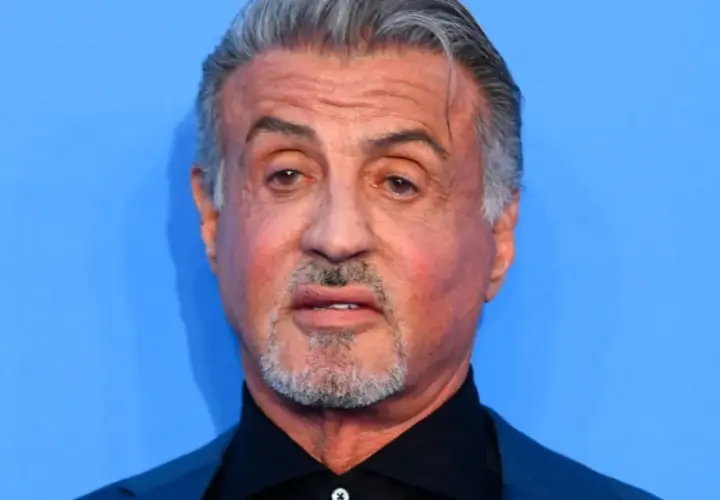 Sylvester Stallone, l'iconico Rocky Balboa oggi, con capelli grigi e barba corta, guarda intensamente.