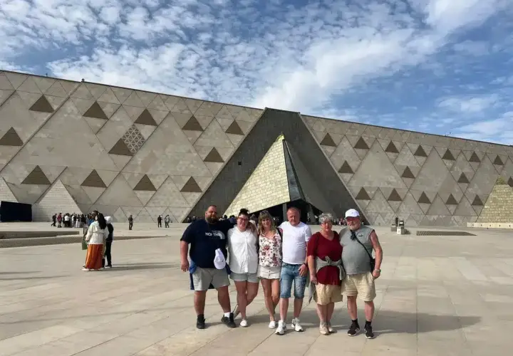 Rodzina pozuje przed nowoczesnym, geometrycznym budynkiem – nowym muzeum w Egipcie.