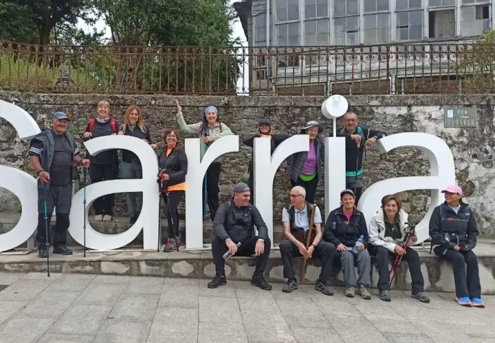 Grupo de peregrinos posa frente a las letras gigantes de Sarria, final de su **tren Santiago Sarria**.