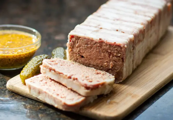 Pasztet zawinięty w boczek, pokrojony na plastry, z ogórkami i musztardą. Idealny do pieczenia w temperaturze 160°C.