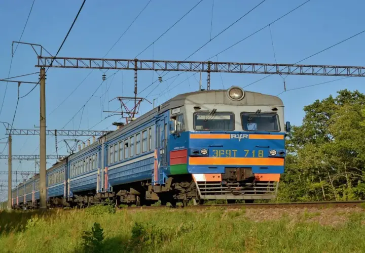 Pociąg elektryczny jedzie po torach, a nad nim widać sieć trakcyjną. To idealny sposób, jak dojechać pociągiem do Kamienia Pomorskiego.